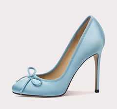 Light blue high-heeled shoe with a bow on a light gray background