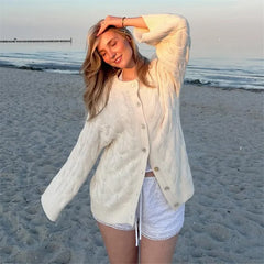 Woman in a white cardigan and shorts on a beach