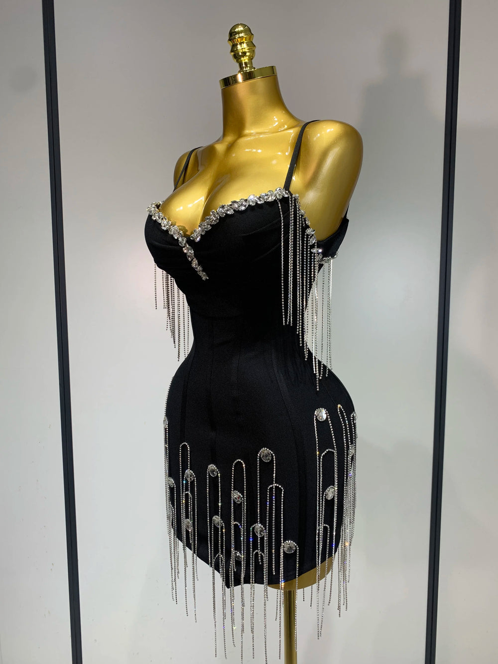 Black dress with silver fringe and embellishments on a mannequin against a neutral background