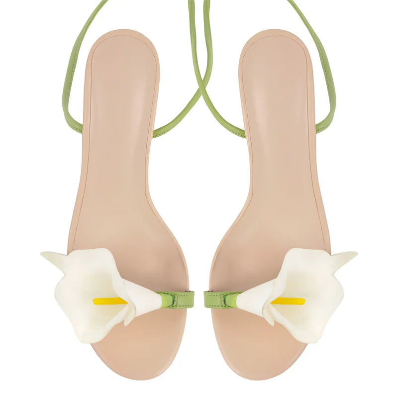 Beige sandals with white floral straps on a white background
