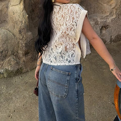 Back view of a lace mock neck sleeveless sheer crop top worn by a person outdoors.