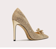 Gold glitter high-heeled shoe with a bow on a light gray background