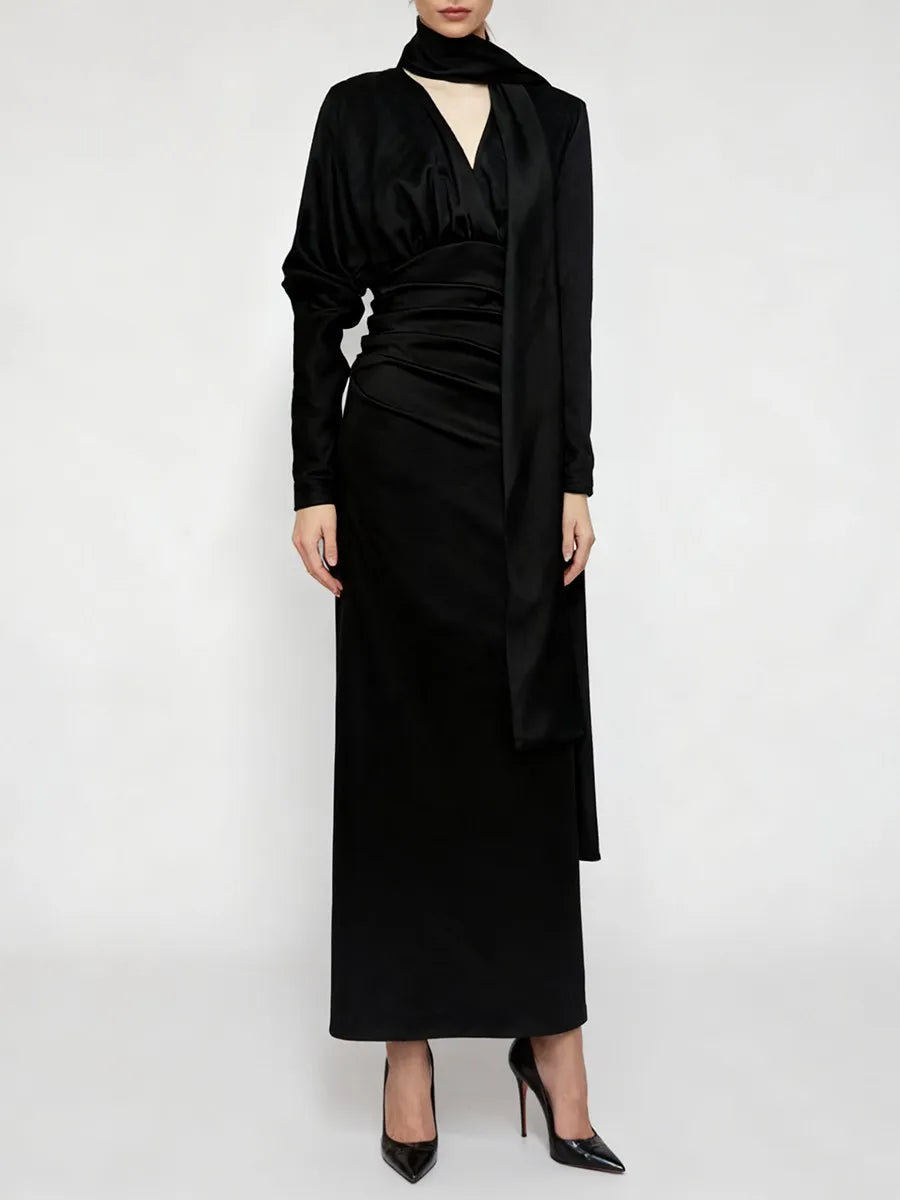 Black dress with long sleeves and a draped design on a white background