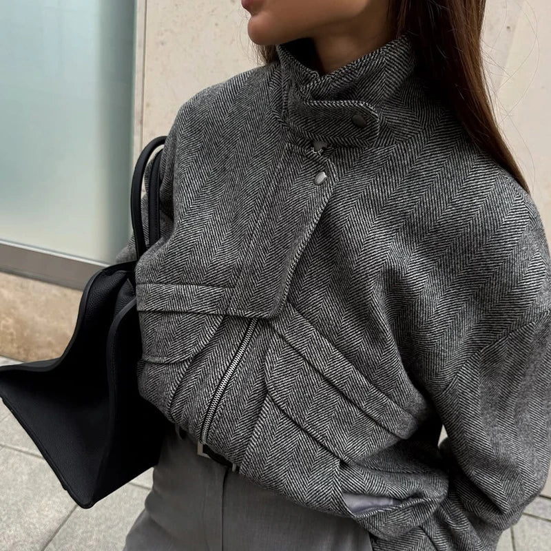 Person wearing a gray textured coat with a black bag.