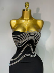 Black dress with silver embellishments on a gold mannequin against a white background