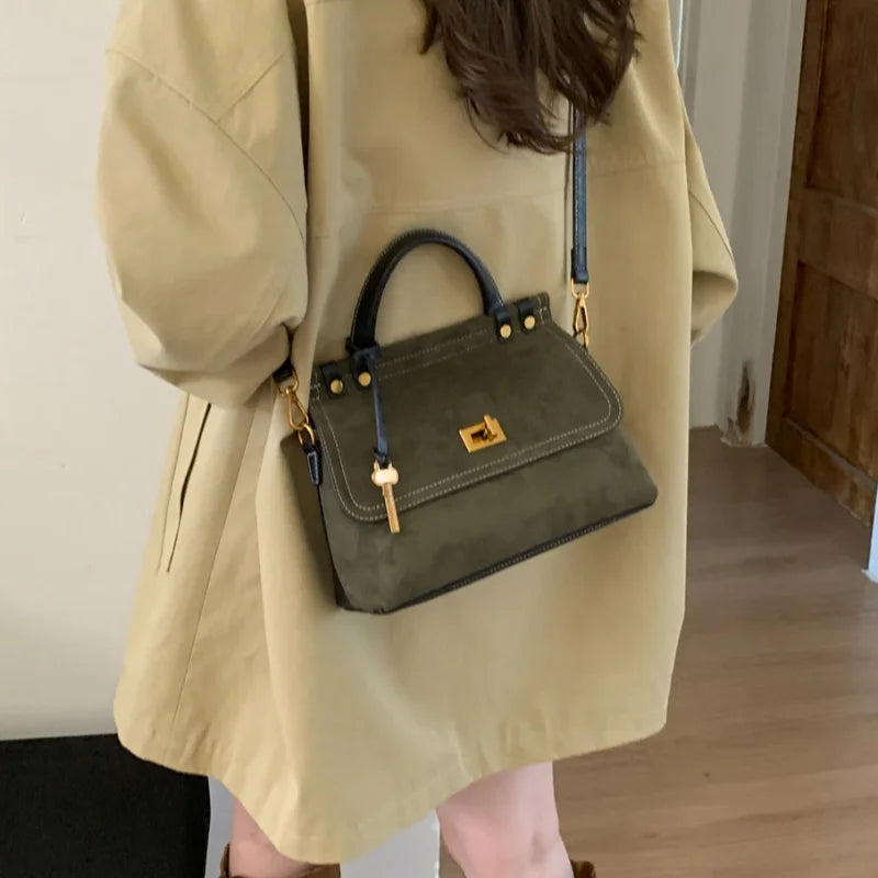 Person wearing a beige coat holding a green handbag indoors.