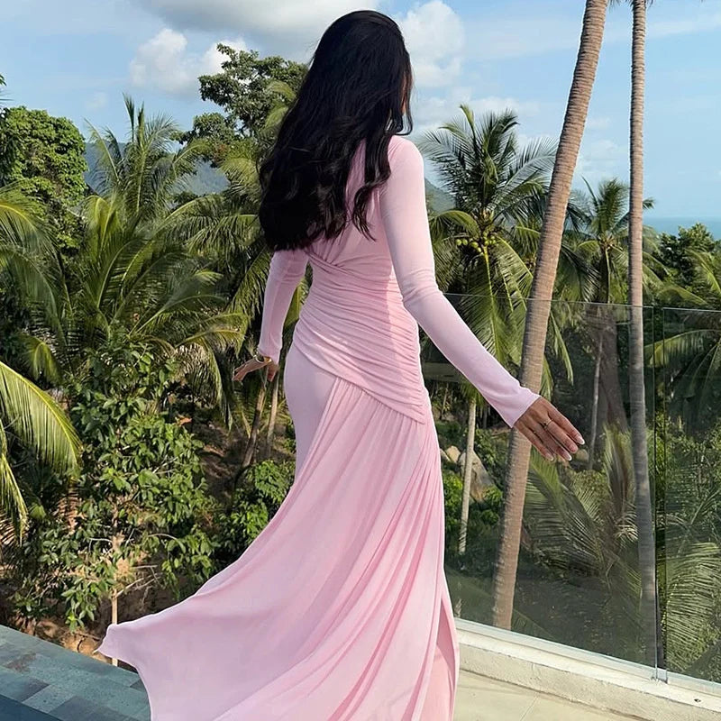 Woman in a pink dress standing in front of tropical trees and palm trees.