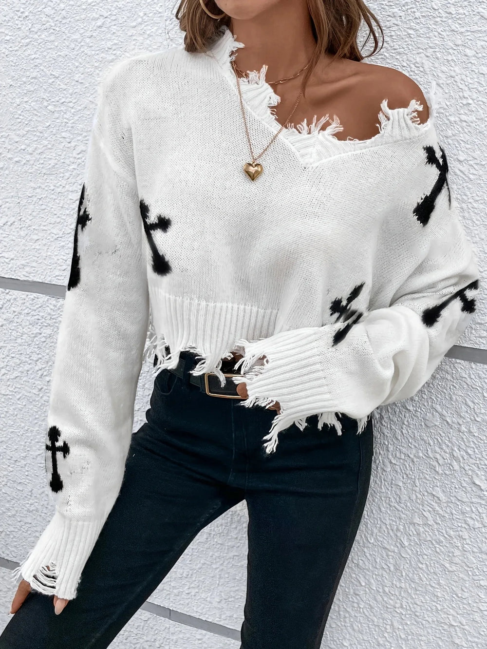 White sweater with black abstract patterns worn by a person against a white background