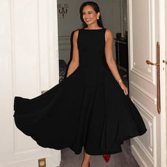 Woman in a black dress standing in a doorway with a flowing skirt.