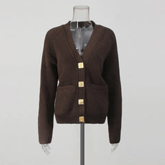 Brown cardigan with gold buttons on a mannequin against a gray background