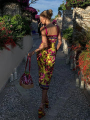 Woman in a colorful dress walking along a stone path with flowers and plants on either side.