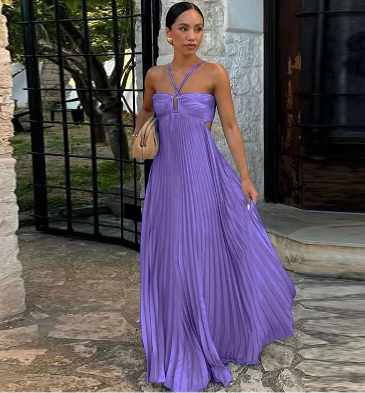 Woman in a purple dress standing outdoors near a stone wall.