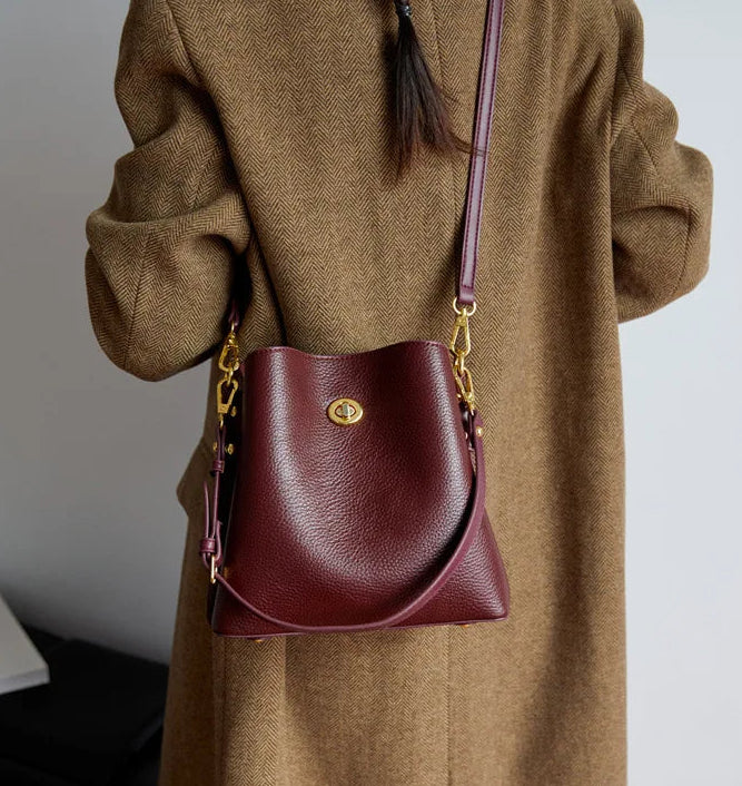 Person wearing a brown coat with a maroon handbag on a plain background