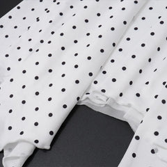 White fabric with black polka dots on a dark surface