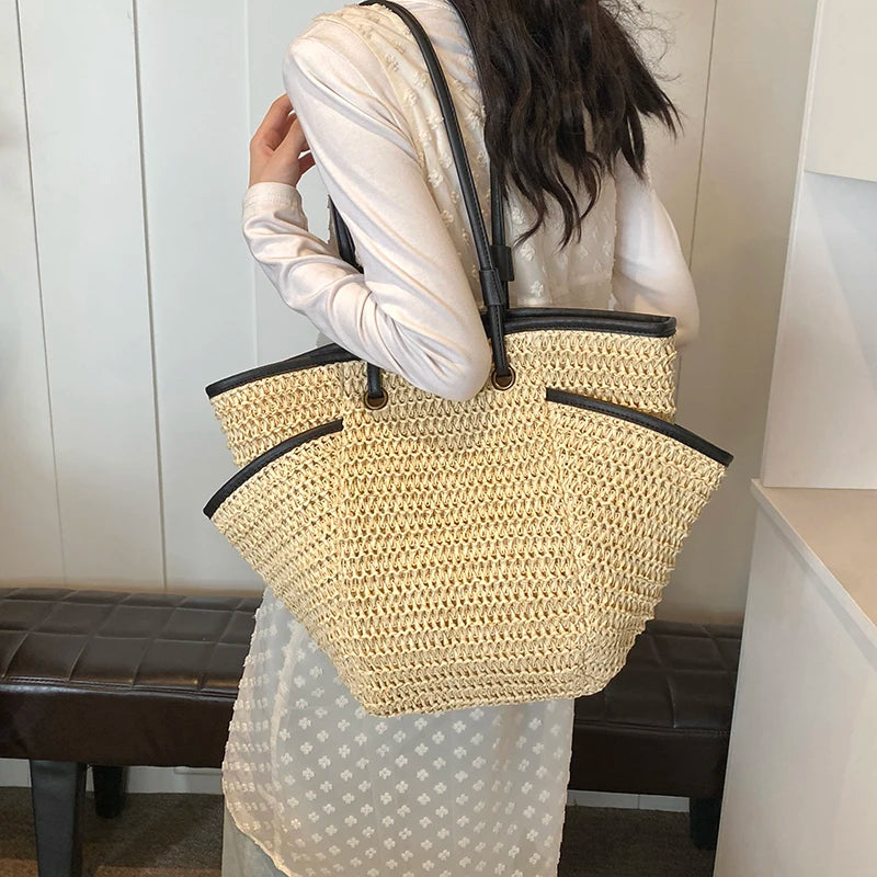 Person holding a woven handbag with a plain background