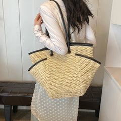 Person holding a woven handbag with a plain background