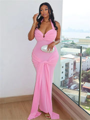 Woman in a pink evening gown standing by a window with a cityscape view.
