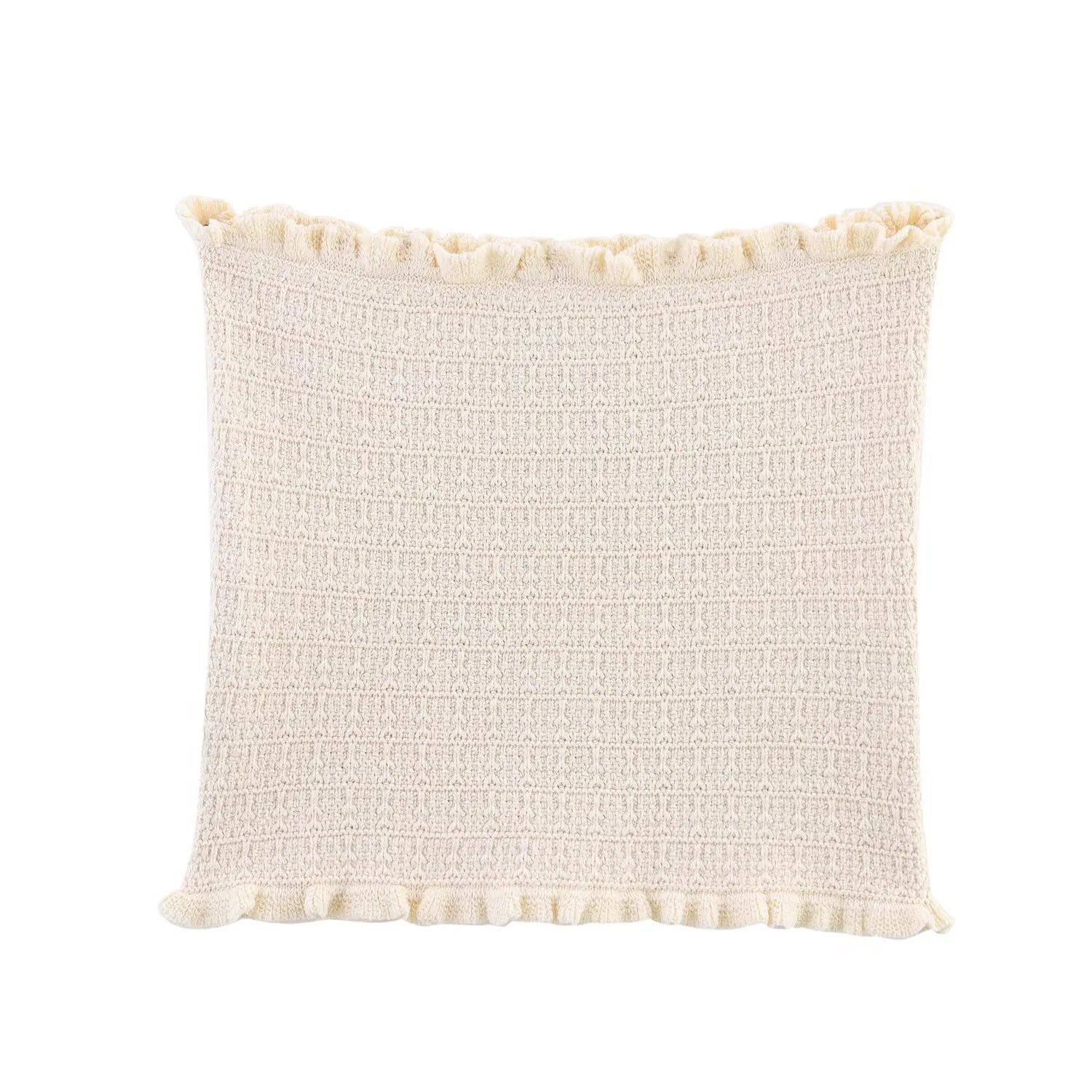 Textured cream pillow with pom-pom trim on a white background