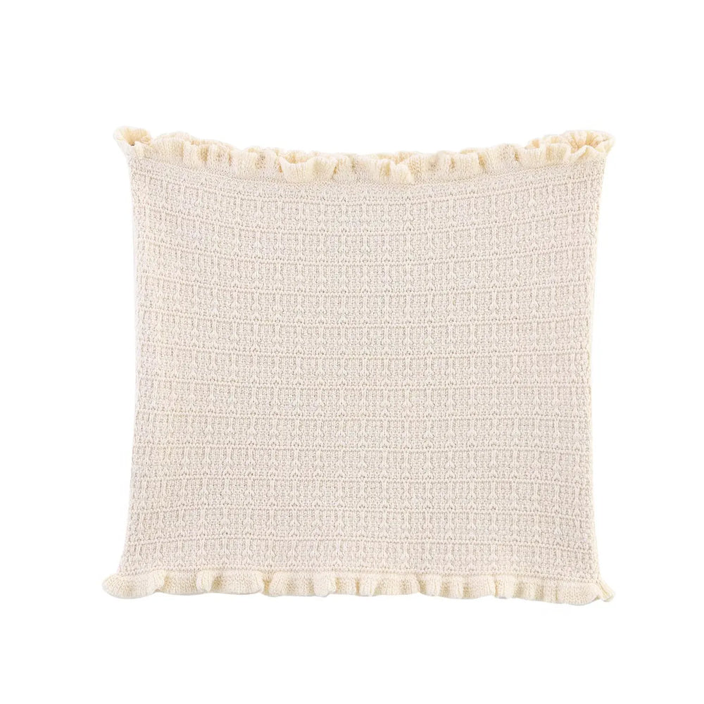 Textured cream pillow with pom-pom trim on a white background