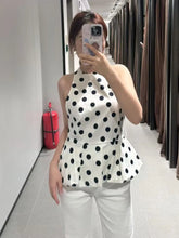 Person wearing a polka dot top and white pants in a fitting room.