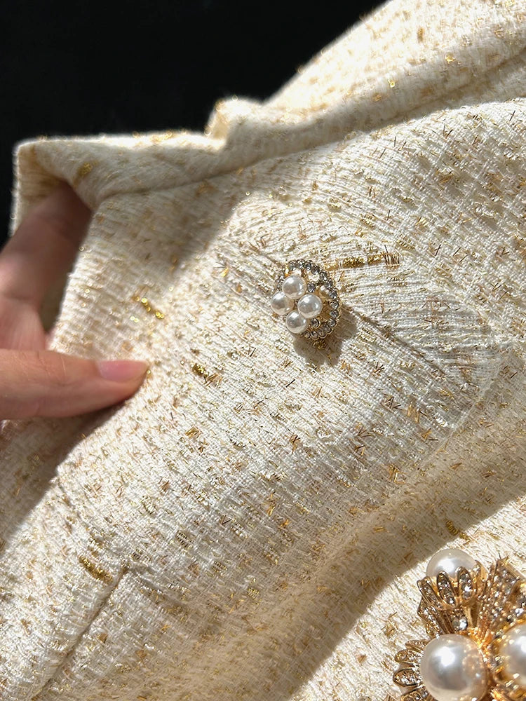 Close-up of a textured fabric with pearl and gold brooches.