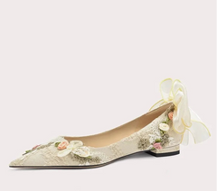 Decorative flat shoe with floral details and a ribbon on a white background