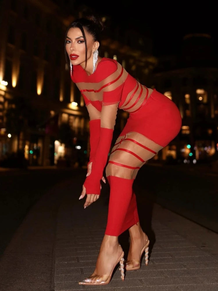 Woman in a red outfit with sheer straps posing on a street at night.