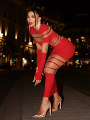 Woman in a red outfit with sheer straps posing on a street at night.