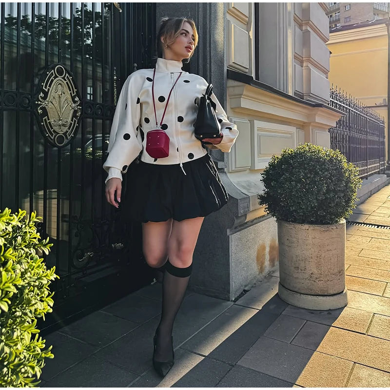 Woman in a stylish outfit standing on a sidewalk with a building in the background