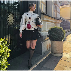 Woman in a stylish outfit standing on a sidewalk with a building in the background