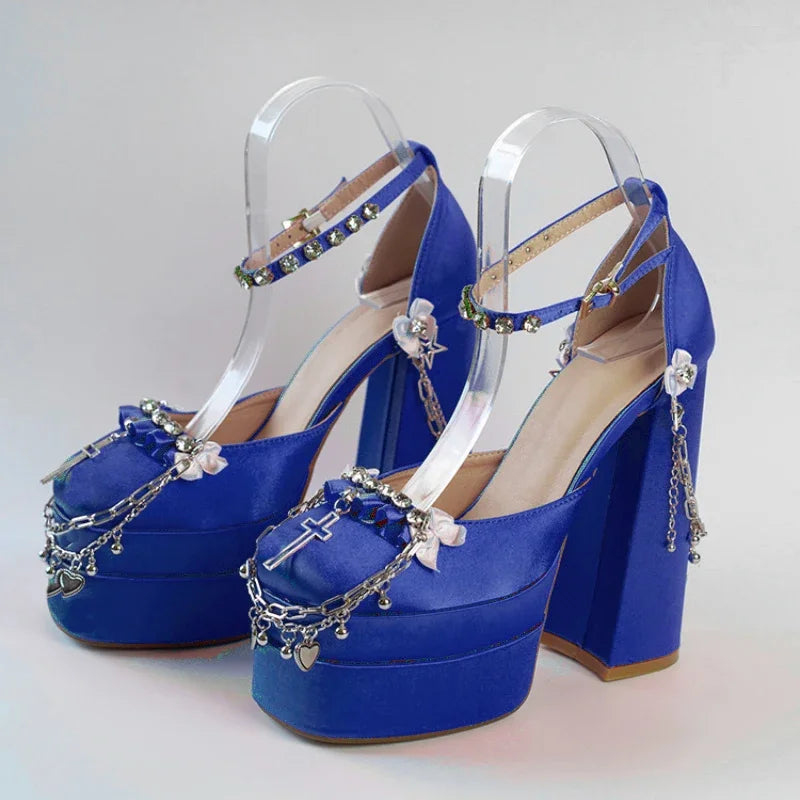 Blue high-heeled shoes with decorative chains on a light gray background