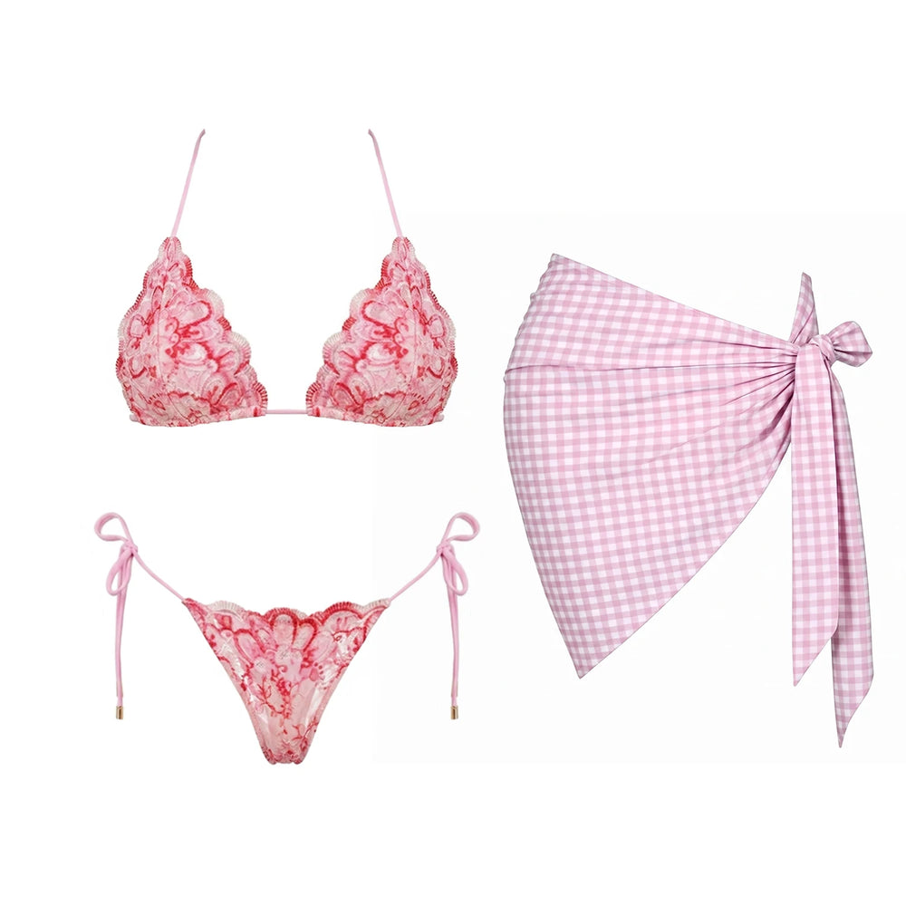 Pink lace bikini top and bottom with a gingham sarong laid out.