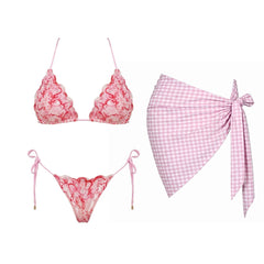 Pink lace bikini top and bottom with a gingham sarong laid out.