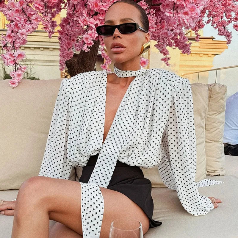 Woman in a polka dot blouse and sunglasses sitting on a couch with cherry blossoms in the background