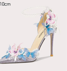 High-heeled shoe with floral design and pearl chain on a white background