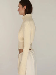 Woman wearing a cream ribbed knit top and skirt set against a plain background