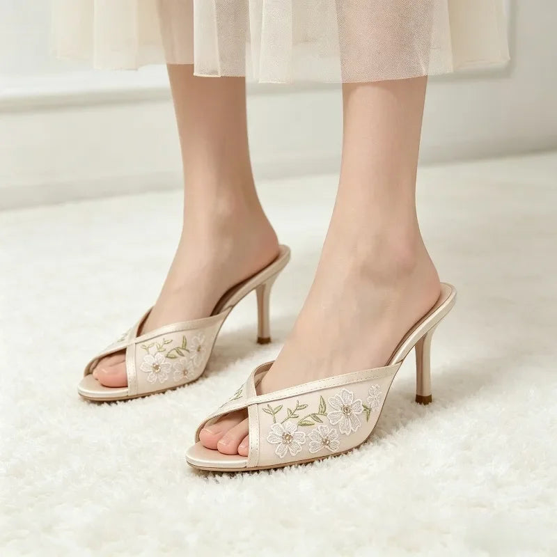 Model wearing beige embroidered floral stiletto mules
