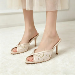 Model wearing beige embroidered floral stiletto mules