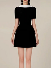Black dress with white collar on a neutral background