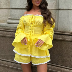 Woman wearing a yellow outfit with white lace details standing on stone steps.