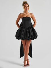 Black strapless dress with a ruffled skirt worn by a model on a light gray background