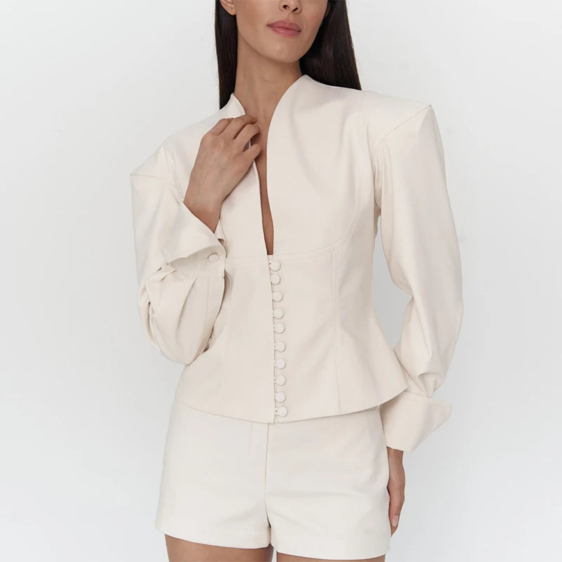 Woman wearing a cream-colored outfit with a jacket and shorts on a white background