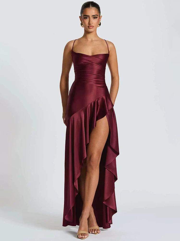 Woman wearing a burgundy satin dress with a high slit on a white background