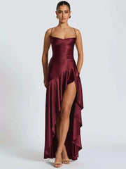 Woman wearing a burgundy satin dress with a high slit on a white background