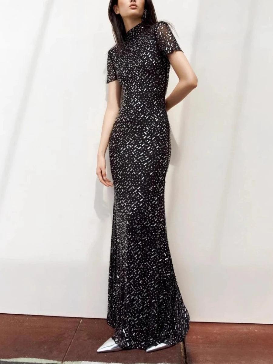 Woman wearing a black sequin evening gown against a white background