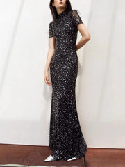 Woman wearing a black sequin evening gown against a white background