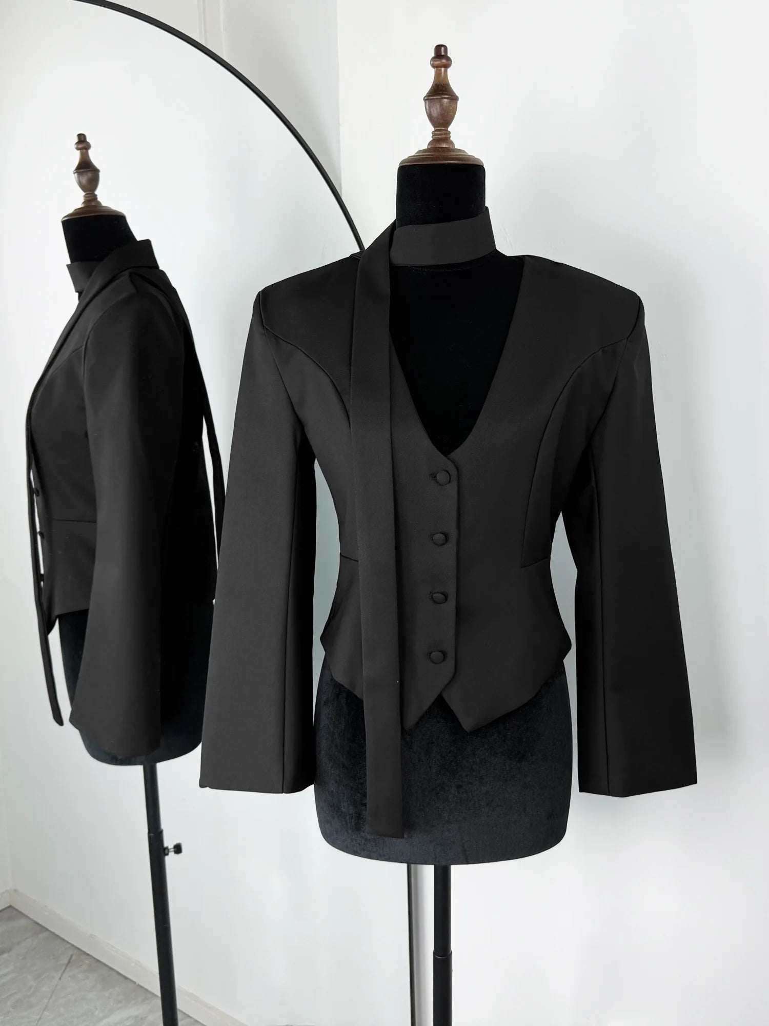Black suit jacket and waistcoat on mannequins against a white background
