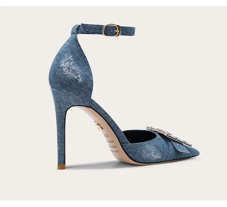 Denim high-heeled shoe with decorative bow on a light gray background