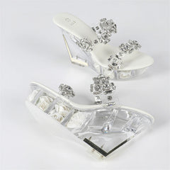 Clear high-heeled shoes with decorative crystals on a white background