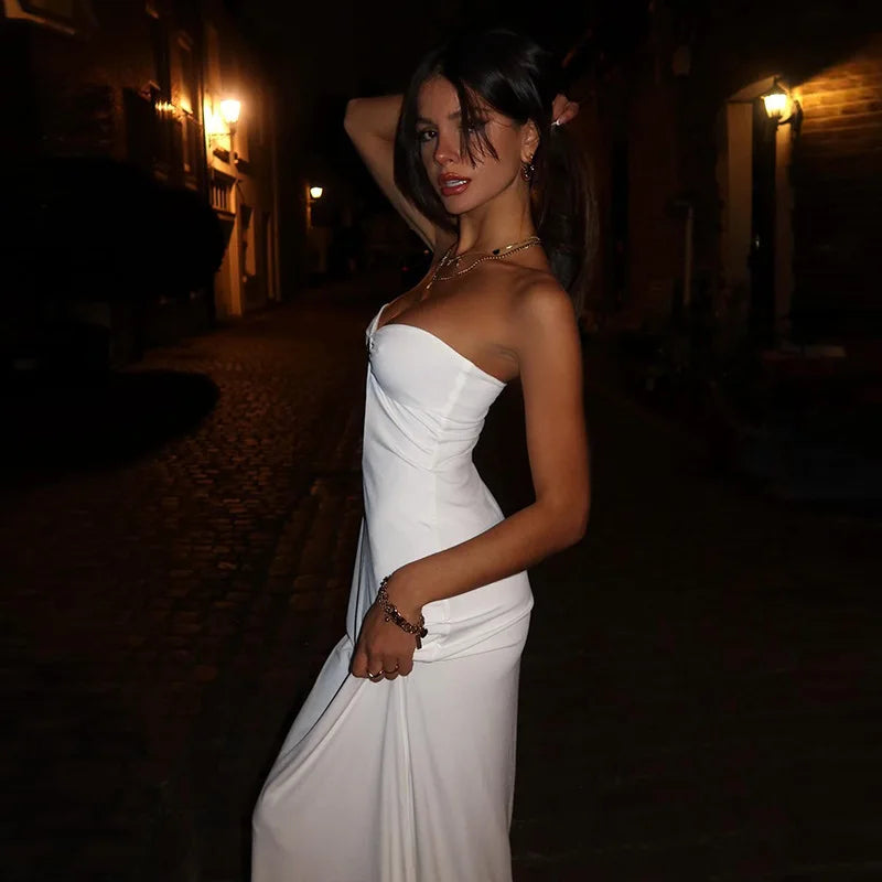 Woman in a white dress standing outdoors at night.